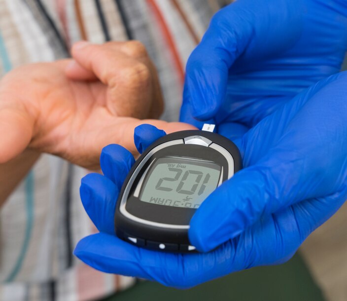A health care professional uses a glucometer to check a patient's blood sugar.