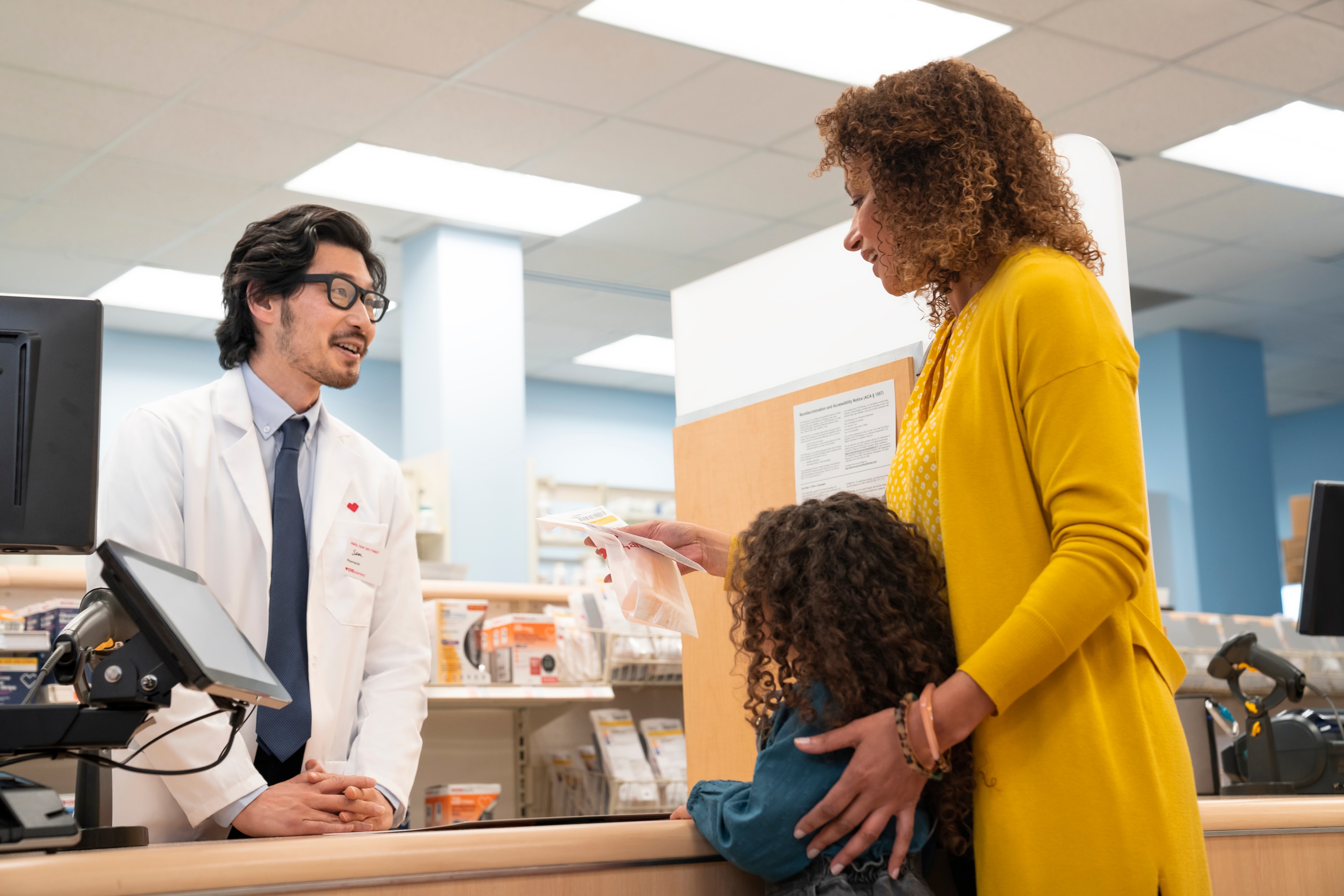 Pharmacist interacting with family across the counter