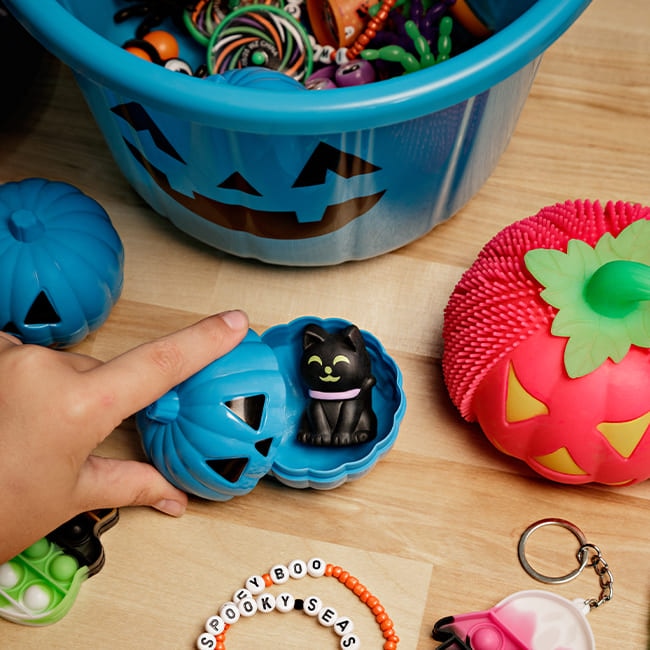 A group of Halloween accessories, including keychains, spider toys, some plastic pumpkins and Halloween-themed bracelets.